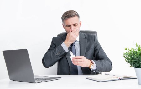Téléchargez les photos : Mature homme dans bureau d'affaires tenir des gouttes nasales. - en image libre de droit