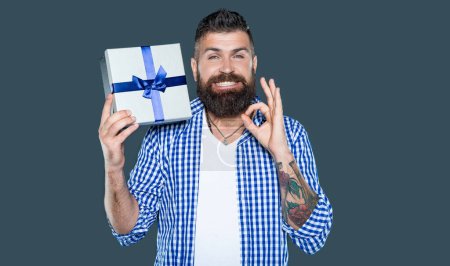 mature bearded guy with wrapped box on grey background.