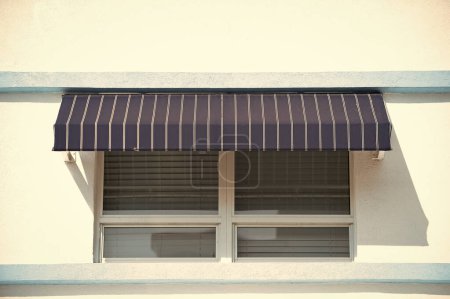 store de fenêtre sur le bâtiment. store de fenêtre rayé. store extérieur. photo de fenêtre store solaire.