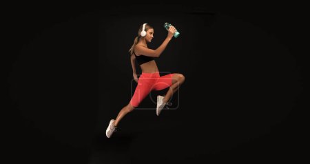 photo of woman sport runner with water bottle. woman sport runner isolated on black. woman sport runner in studio. woman sport runner on background.