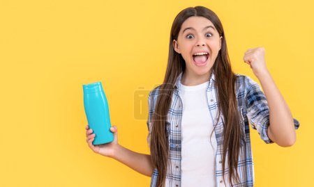 surprised teen girl with shampoo cosmetics in studio. teen girl with shampoo cosmetics on background. photo of teen girl with shampoo cosmetics. teen girl with shampoo cosmetics isolated on yellow.