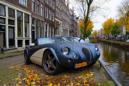 Foto de Ámsterdam, Países Bajos - 15 de noviembre de 2021: Wiesmann GT MF5 roadster vintage convertible classic sport car parking at autumn river, corner view. - Imagen libre de derechos