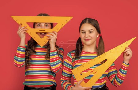 Téléchargez les photos : Sourire écolières tenir maths outil de triangle. - en image libre de droit