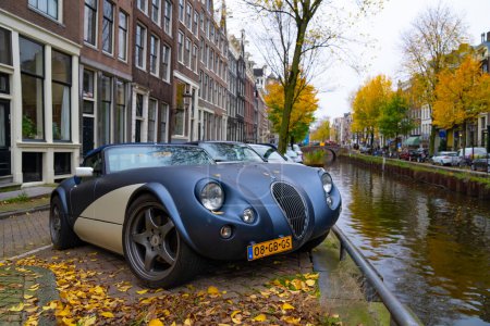 Foto de Ámsterdam, Países Bajos - 15 de noviembre de 2021: Wiesmann GT MF5 roadster retro convertible classic sport car parking at autumn river, corner view. - Imagen libre de derechos