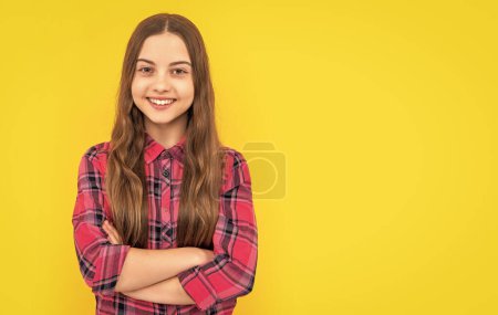 Foto von Teenie-Mädchen mit langen Haaren trägt kariertes Hemd, Kopierraum. Teenager Mädchen isoliert auf gelb. Teenie-Mädchen im Studio. teen girl auf hintergrund.