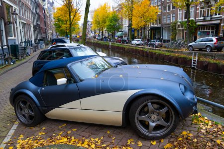 Foto de Ámsterdam, Países Bajos - 15 de noviembre de 2021: Wiesmann GT MF5 roadster retro convertible classic sport car parking at autumn river, side view. - Imagen libre de derechos
