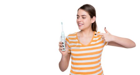 Téléchargez les photos : Sourire jeune femme pointe du doigt sur brosse à dents électrique isolé sur fond blanc. - en image libre de droit