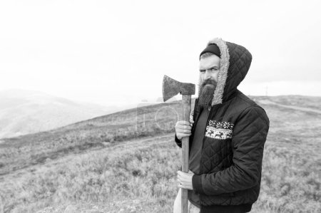 Foto de Bearded man lumberjack hold axe outdoor, advertisement. bearded man lumberjack has axe. bearded man lumberjack with axe. photo of bearded man lumberjack holding axe in the mountain. - Imagen libre de derechos