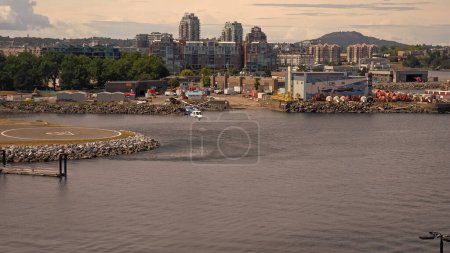 Photo for Victoria, Canada - June 28, 2019: helicopter taking off helipad in heliport in sea ocean harbor on cityscape. - Royalty Free Image