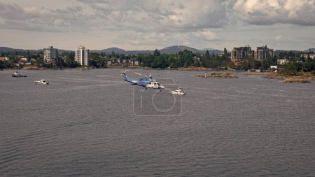 Photo for Victoria, Canada - June 28, 2019: helicopter flying over ocean sea water in city harbor. - Royalty Free Image