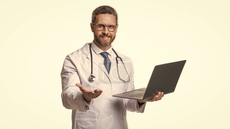 Photo for Cheerful doctor promoting emedicine isolated on white. doctor offering emedicine in studio. doctor presenting emedicine on background. photo of emedicine and doctor man with laptop. - Royalty Free Image