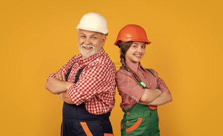 Photo for Positive child and grandfather builder in helmet on yellow background. - Royalty Free Image