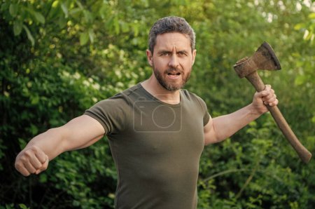 Photo for Man threatening with hatchet. man threatening with hatchet wearing shirt. man threatening with hatchet outdoor. photo of man threatening with hatchet. - Royalty Free Image