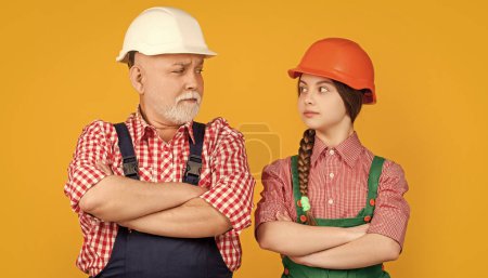 Photo for Serious kid and grandfather builder in helmet on yellow background. - Royalty Free Image