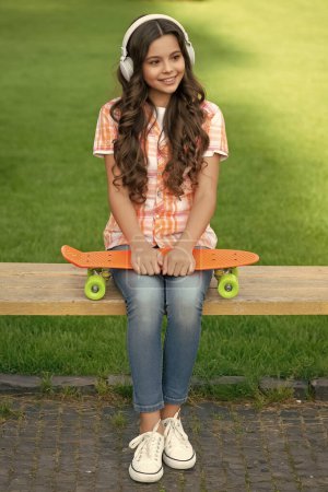 Photo for Happy teen girl with skateboard outdoor. teen girl with skateboard in headphones. teen girl with skateboard outside. photo of teen girl with skateboard listen music. - Royalty Free Image