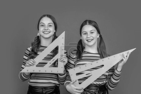 Photo for Happy school girls hold math tool of triangle. - Royalty Free Image