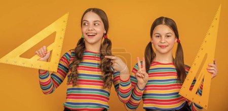 Photo for Amazed school children hold math tool of triangle. - Royalty Free Image