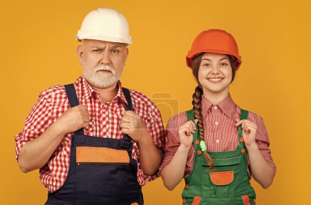 Photo for Child and grandfather builder in helmet on yellow background. - Royalty Free Image