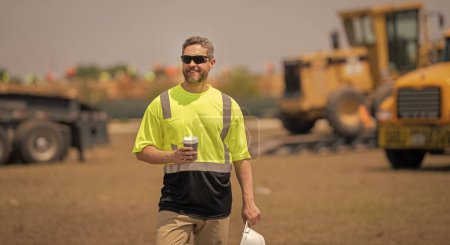 Photo for Contractor man at construction site. contractor check building during break. male contractor at working location. worker at coffee break. contractor in hard hat and safety vests in building site. - Royalty Free Image