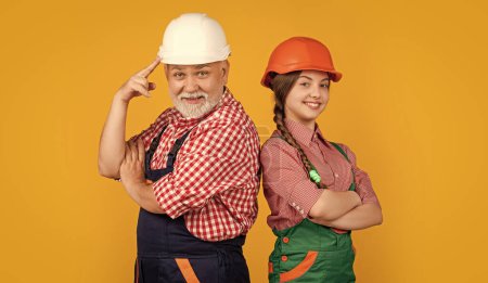 Photo for Smiling kid and grandfather builder in helmet on yellow background. - Royalty Free Image