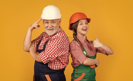 Photo for Happy girl and grandfather builder in helmet on yellow background. thumb up. builder concept. fathers day - Royalty Free Image