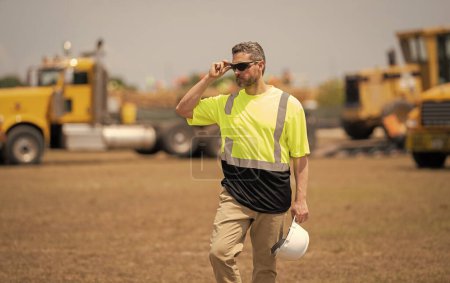 Photo for Confident contractor inspecting progress of new construction project. contractor review construction site. Construction contractor overseeing building. contractor walking at site of building project. - Royalty Free Image