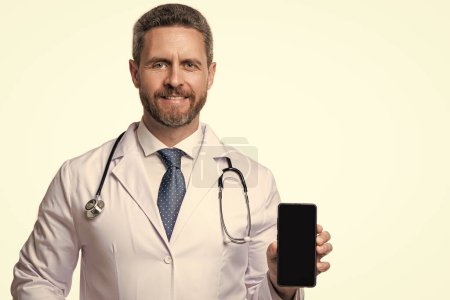Photo for Medical man show telehealth in studio, copy space. medical man show telehealth on background. photo of medical man show telehealth on phone screen. medical man show telehealth isolated on white. - Royalty Free Image