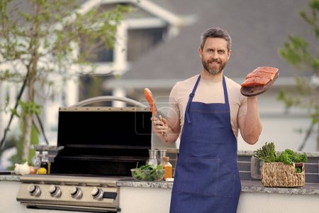 Photo for Happy grilled salmon fish at man wear chef apron. photo of chef with grilled salmon. chef with grilled salmon. chef man cooking grilled salmon outdoor. - Royalty Free Image
