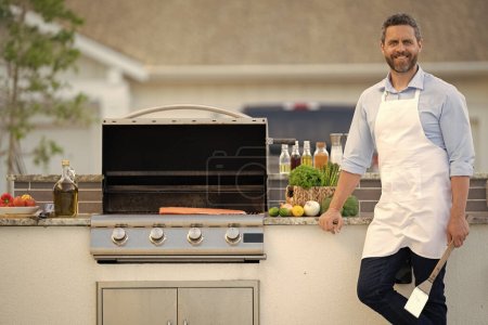 Photo for Cheerful man grilling salmon fillet at backyard, copy space advertisement. photo of man grilling salmon fillet for barbecue. man grilling salmon fillet. man grilling salmon fillet outdoor. - Royalty Free Image