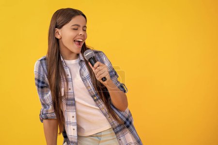 Foto de Joven cantante de karaoke chica mantenga micrófono, espacio para copiar. adolescente chica cantante hold mic en estudio. joven cantante realizar karaoke aislado en el fondo. Con micrófono en mano cantante adolescente. - Imagen libre de derechos