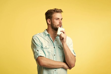 Mann hält Parfümerie isoliert auf gelb. Mann mit Parfümerie im Studio-Hintergrund. Foto eines Mannes mit Parfümerie. Mann mit Parfümerie.
