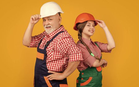 Photo for Glad child and grandfather builder in helmet on yellow background. - Royalty Free Image
