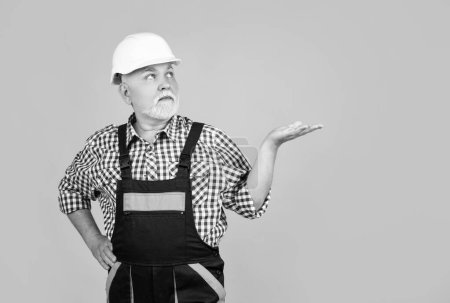 Photo for Serious old man builder in helmet on yellow background. - Royalty Free Image