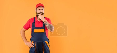 Photo for Thoughtful bearded man technician in work clothes on yellow background with copy space. - Royalty Free Image
