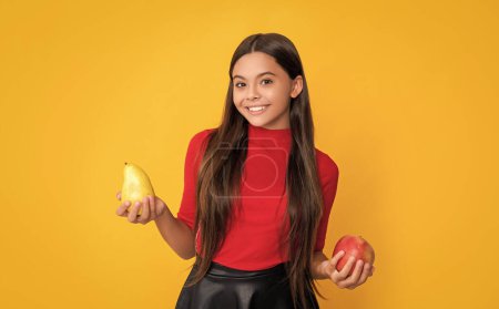 souriant enfant tenir pomme et poire sur fond jaune.