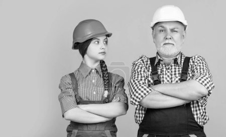 Photo for Serious child and grandfather builder in helmet on yellow background. - Royalty Free Image