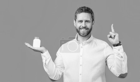 Photo for Man with medication and raised finger isolated on blue background. man hold medication in studio. man presenting medication jar. photo of man holding medication, healthcare. - Royalty Free Image
