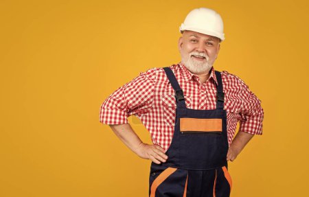 Photo for Happy senior man builder in hard hat on yellow background. - Royalty Free Image