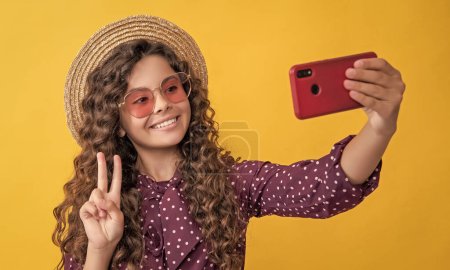 Téléchargez les photos : Happy girl with curly hair taking selfie on phone. peace. - en image libre de droit