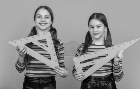 Photo for Happy school children hold math tool of triangle. - Royalty Free Image