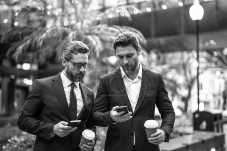Photo for Business colleagues with phone outdoor. business colleagues with phone in suit. photo of business colleagues with phone and coffee. business colleagues with phone in the street. - Royalty Free Image