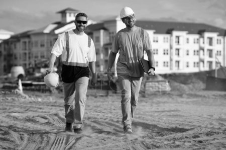 Photo for Positive engineer men walking at construction site. engineer men at construction site wearing hardhat. engineer men at construction site outdoor. photo of engineer men at construction site. - Royalty Free Image