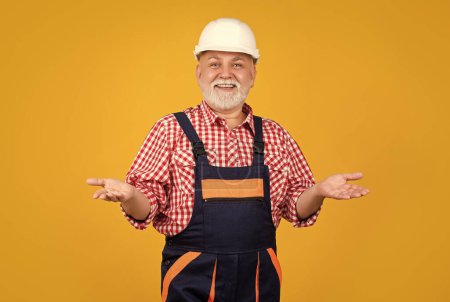 Photo for Happy mature man builder in helmet on yellow background. - Royalty Free Image