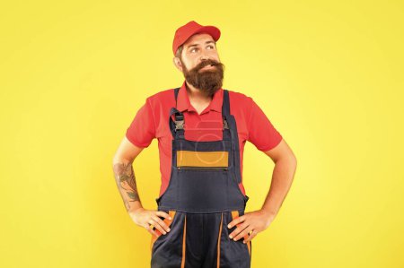 Photo for Thinking bearded man loader in work clothes on yellow background. - Royalty Free Image