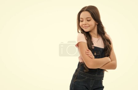 Happy teenager smiling in trendy teen wear studio. Teen girl keeping arms crossed isolated on white. Teen model in casual fashion style, copy space.