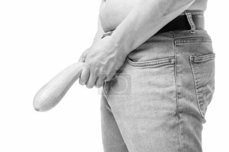 Photo for Man crop view holding zucchini as limp-dick at crotch level imitating impotence isolated on white. - Royalty Free Image