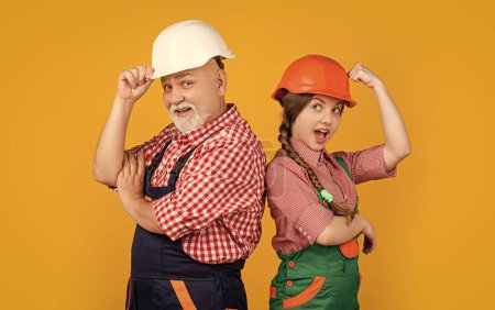 Photo for Surprised child and granddad builder in helmet on yellow background. - Royalty Free Image