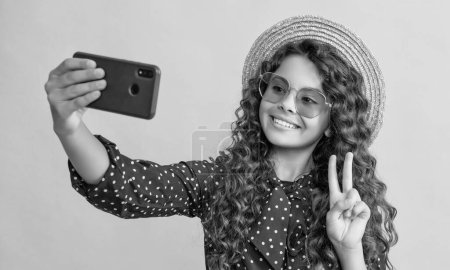 Foto de Happy girl with curly hair taking selfie on phone. peace. - Imagen libre de derechos