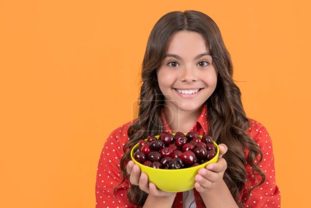 Photo for Happy teen girl hold cherry bowl on yellow background. copy space. - Royalty Free Image