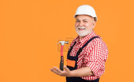 happy mature man carpenter in helmet on yellow background.